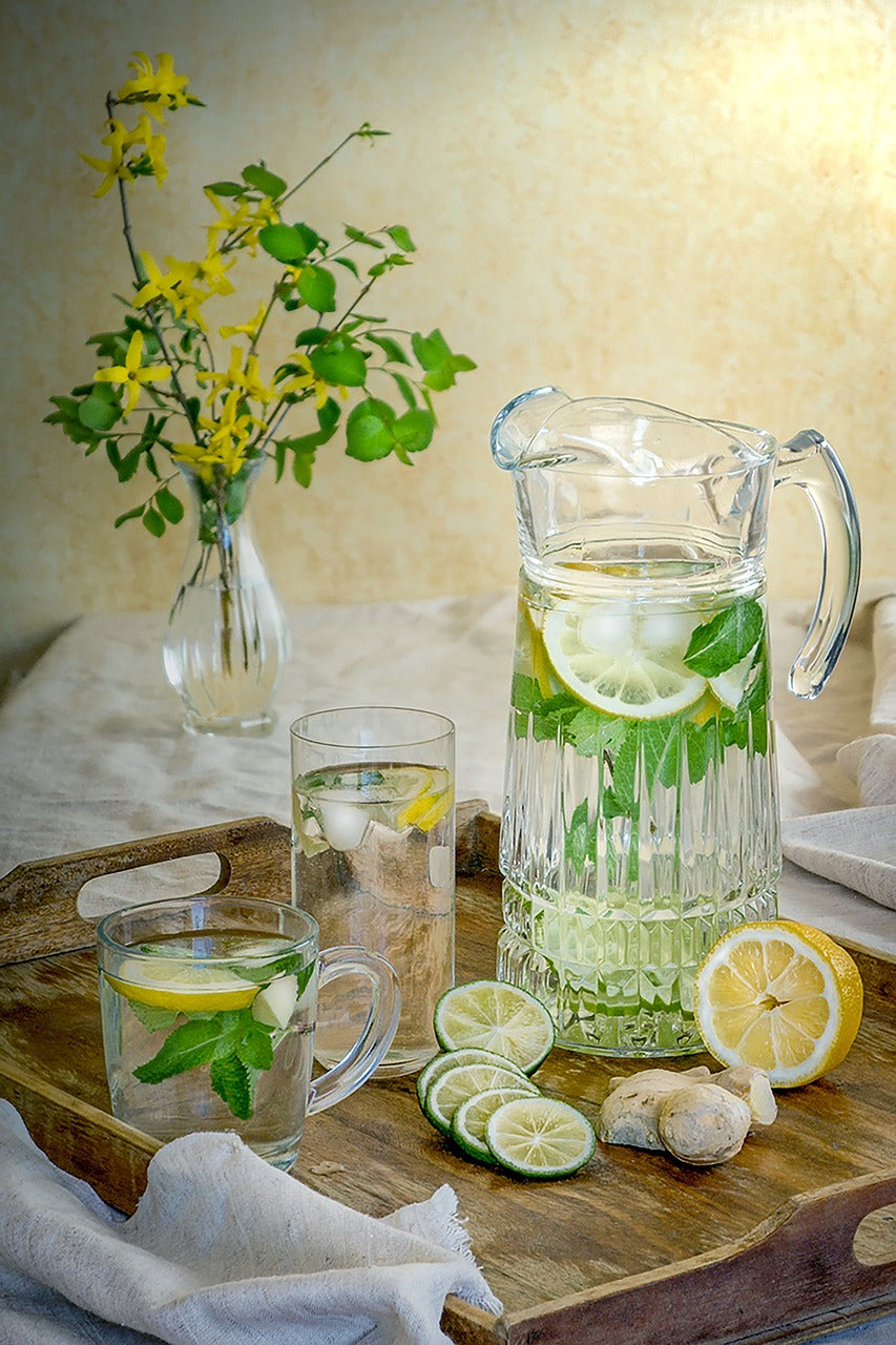 Wasserkrug mit Gläsern, Limetten, Orangen, Minze